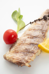 Fish fried on the grill and served on a plate with fresh vegetables