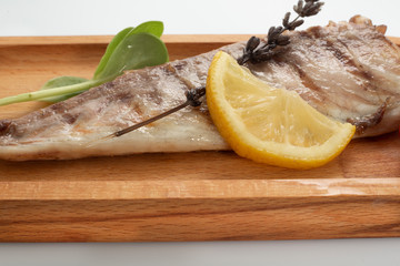 Fish fried on the grill and served on a plate with fresh vegetables