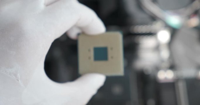 CPU processor comes into focus held by technician with white latex rubber gloves. Custom PC build concept, upgrading computer hardware.
