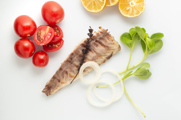 Fish fried on the grill and served on a plate with fresh vegetables
