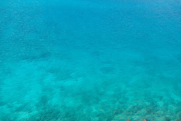 Blue surface of sea. Water is calm, just a little waves from breeze. It's possible to see some underwater reefs