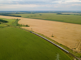 Aerial drone view. The train passes between the fields.