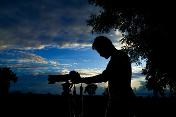 Silhouette of a man photographer with dslr camera during taking photos at sunset