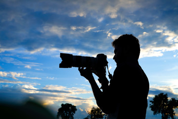 Silhouette of a man photographer with dslr camera during taking photos at sunset