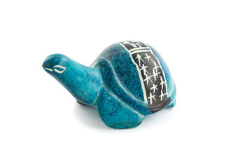 Figurine of a turtle made of stone with carvings on the shell on a white background.