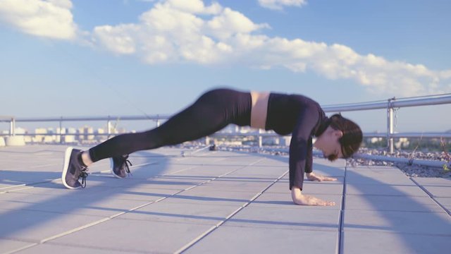 Young pretty woman practicing jumping push-ups, physical activity, body strength