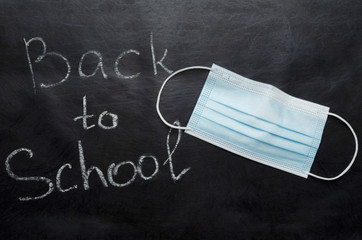 Top view of facial mask and words Back to School on the black surface.Concept of distatnce learning