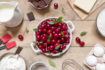Top view raw ingredients for cooking cherry pie on wooden background. Bakery background.