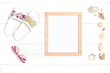 Wooden frame with flip flops and shells on a light wooden background