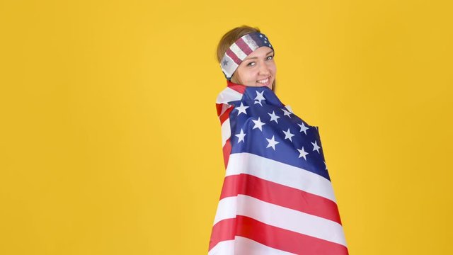 Young Happy Patriot Girl Wearing Sportswear and Headband Waving and Wrapping in the American Flag. celebrating Independence Day