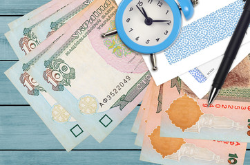 100 Ukrainian hryvnias bills and alarm clock with pen and envelopes. Tax season concept, payment deadline for credit or loan. Financial operations using postal service