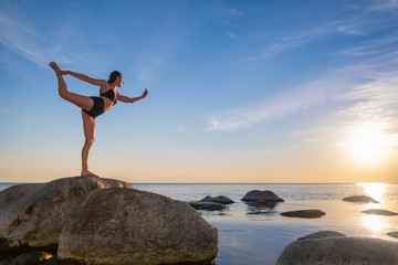 Anonymous woman balancing on stone in Warrior pose