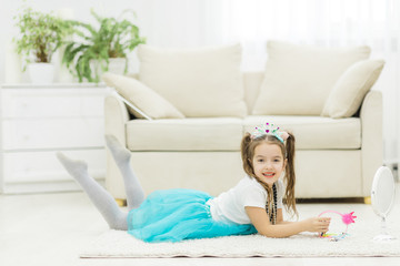 Photo of little girl wearing blue skirt laying on the floor.