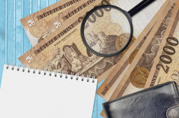 2000 Hungarian forint bills and magnifying glass with black purse and notepad. Concept of...