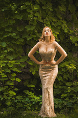 Evening dress concept. Redhead woman in evening dress demonstrates her feminine figure, a round,...