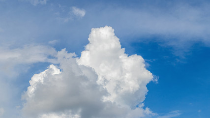 Naklejka na ściany i meble White curly cloud on a blue sky in sunny weather