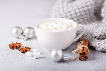 Fototapeta na wymiar White cup with hot chocolate and marshmallow, sweater, cinnamon. Cozy christmas composition. Hygge concept Soft focus
