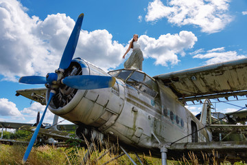Young beautiful woman stands on an abandoned plane