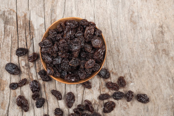 Organic dried Raisins in brown wood bowls on vintage wooden table background
