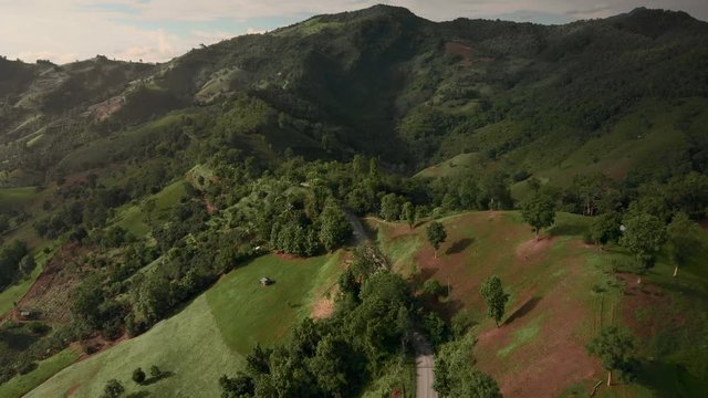 Sunset aerial mountain valey with green farm fields and road