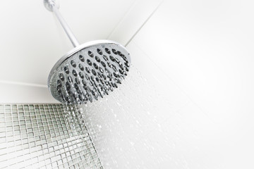 A shower head with flowing water in bathroom