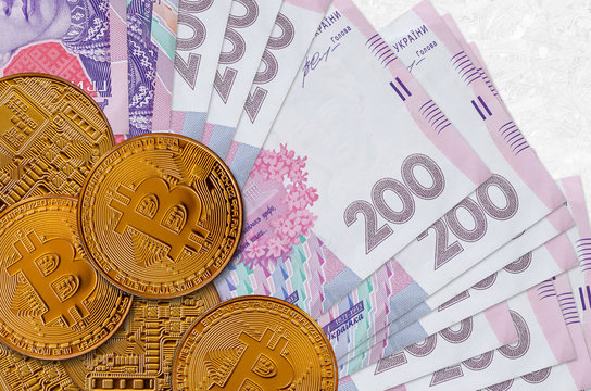 200 Ukrainian hryvnias bills and golden bitcoins. Cryptocurrency investment concept. Crypto mining or trading