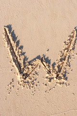 W - Alphabet letter written on sand 