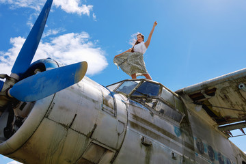 Young pretty woman stands on an abandoned plane