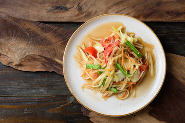 Thai food, Spicy papaya salad (Som Tum) on wooden table, Top view