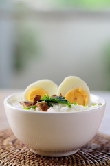 Asian food, Rice soup with boiled egg, grilled mushroom and spinach in a bowl on woven rattan sheet