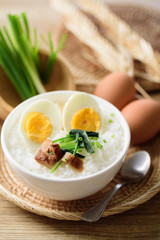 Asian food, Rice soup with boiled egg, grilled mushroom and spinach in a bowl on woven rattan sheet