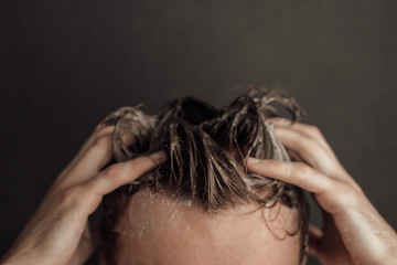 a man washes his hair: hands and wet hair in shampoo foam - obrazy, fototapety, plakaty
