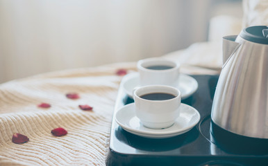 Coffee in bed. Morning breakfast with black coffee in bedroom. Two cups of coffee on bed in luxury hotel honeymoon suite. Romantic weekend for two.