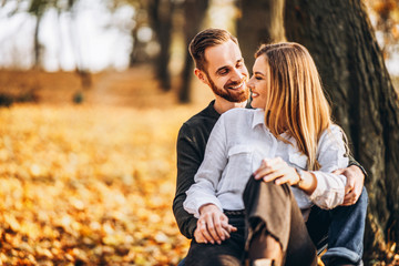 Fototapeta premium Man and woman hugging and smiling on the background of autumn trees.