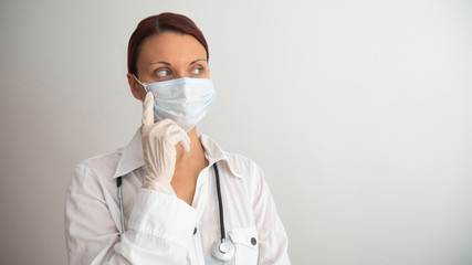 Female doctor with medical mask, stethoscope and latex gloves on white background.