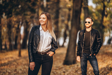 Beautiful young woman posing in autumn park. I the background is a blurred silhouette of her boyfriend. Love story