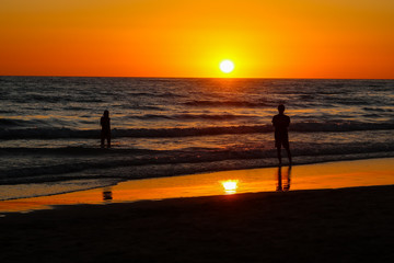 Fototapeta premium Silhouettes of people taking photos at sunset on the beaches of Cadiz, Spain