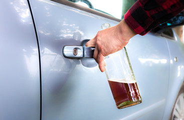Drunk driver is opening the car door. Man is holding a bottle and keys. Alcohol while driving....