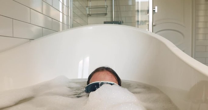 Woman in a mask dives into the water in the bathroom and emerges. Female missed the quarantine vacation