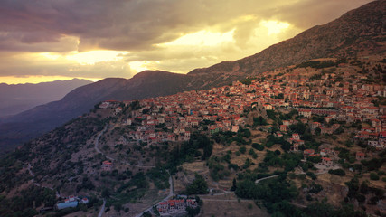 Aerial drone photo of beautiful sunset with golden colours and clouds over picturesque and traditional village of Arachova, Viotia prefecture, Greece