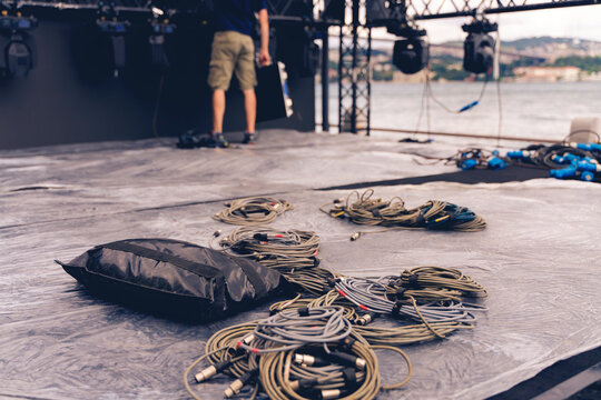 Installation of professional sound, light, video and stage equipment for a concert. Stage lighting equipment is clamped on a truss for lifting. Flight cases with cables.