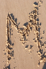 M - Alphabet letter written on sand 