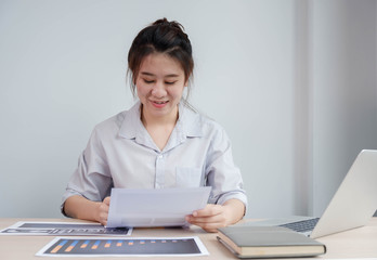 Portrait beautiful asian businesswoman working in her home, office, looking at graphs, financial markets, her business, and paying much attention.