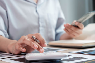 Fototapeta premium businesswoman or an accountant uses a calculator to calculate prices. And customer proposals for future financial spending for balance and prosperity, using graphs to analyze