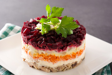Traditional Russian herring salad with beetroot and carrots on black background