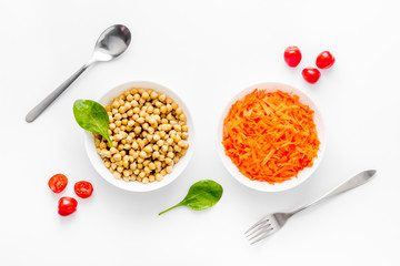 Vegetarian meal. Chickpeas and carrot in bowls on white table top view