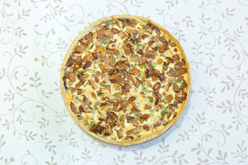 Traditional French pie, quiche with chanterelles and green onions top view on a light background with a vegetable pattern. Pizza with mushrooms. Home cooking, food preparation, vegetarian cuisine.