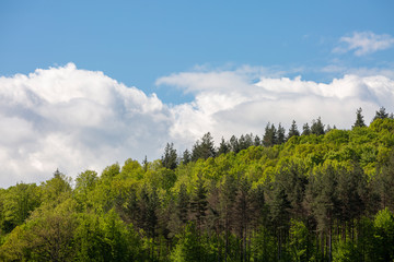 Scenic green rolling hills against the blue sky with clouds.