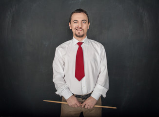 Smirking teacher or business man with pointer on blackboard