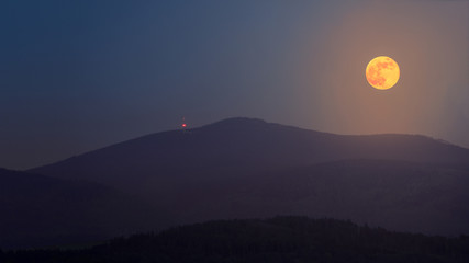 The full flower moon - May, 07, 2020. The rising moon over the mountain peaks of the Sudetes.